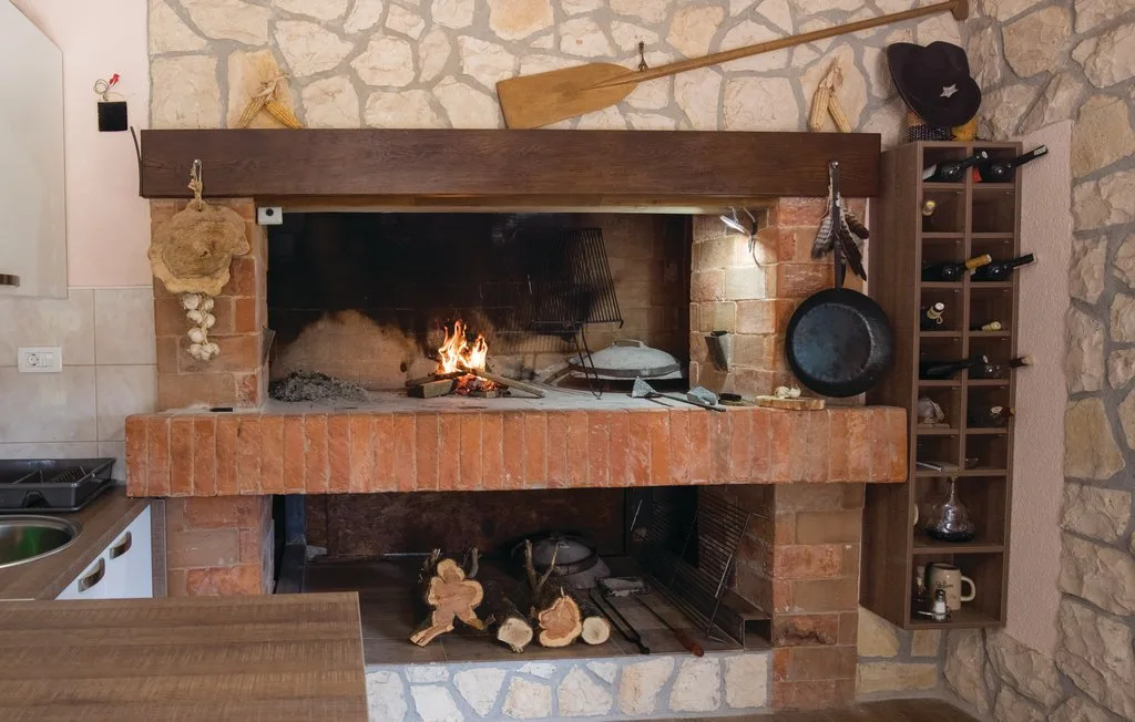 Una chimenea de piedra con un pequeño fuego encendido bajo una repisa de madera.
