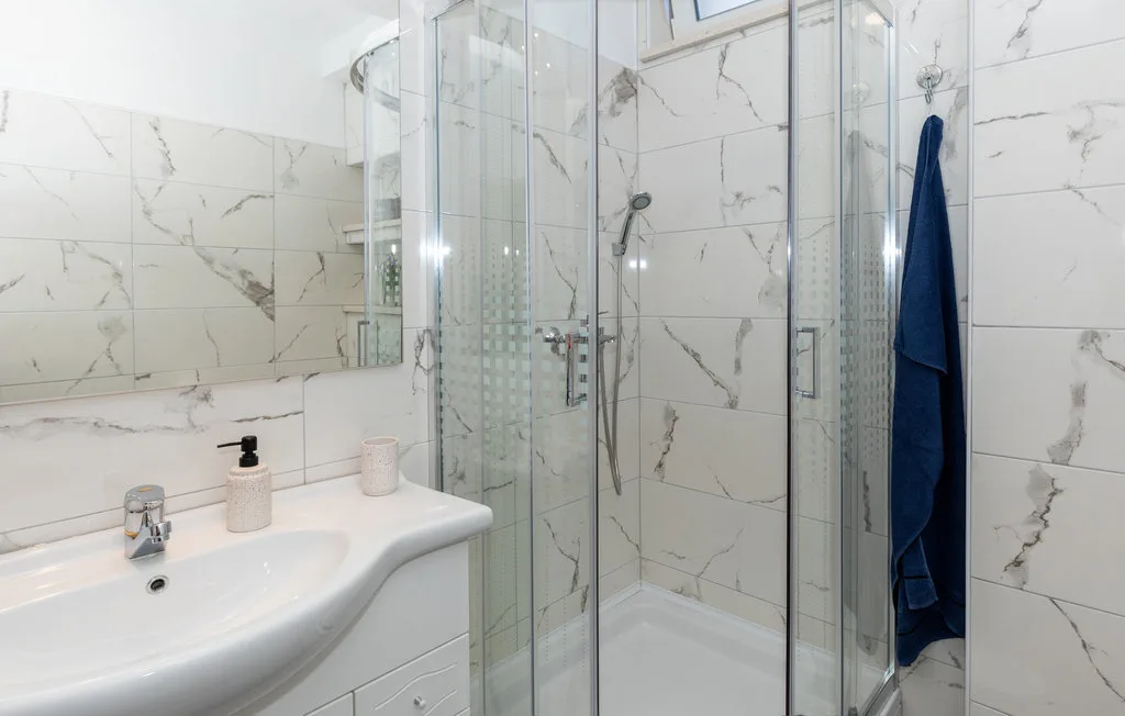 Un baño luminoso con un lavabo junto a una ducha de vidrio.