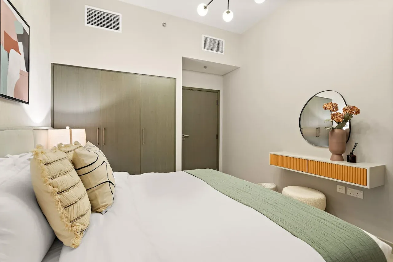 A bedroom with a neatly made bed and built-in storage.
