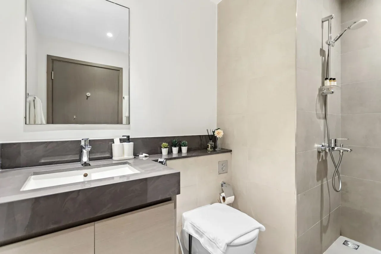A bathroom with a sink, mirror, and shower.