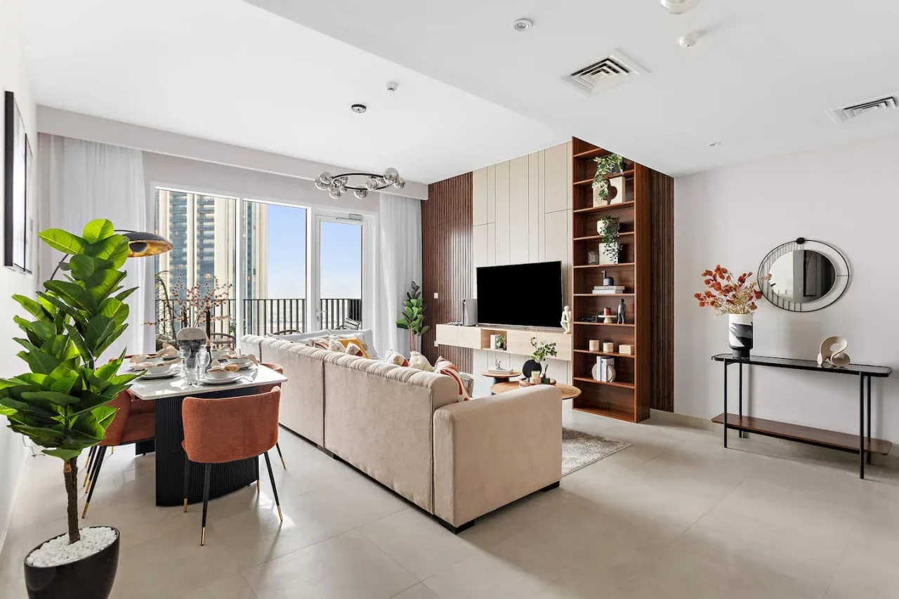 A bright living and dining area with seating, a television, and large windows.