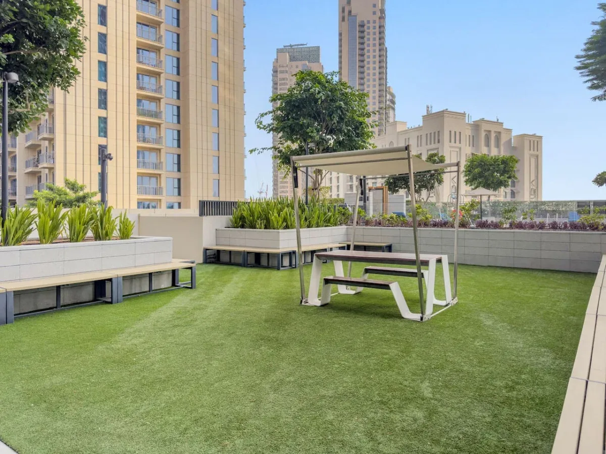 A rooftop terrace with artificial grass, raised planters, and a shaded seating area.