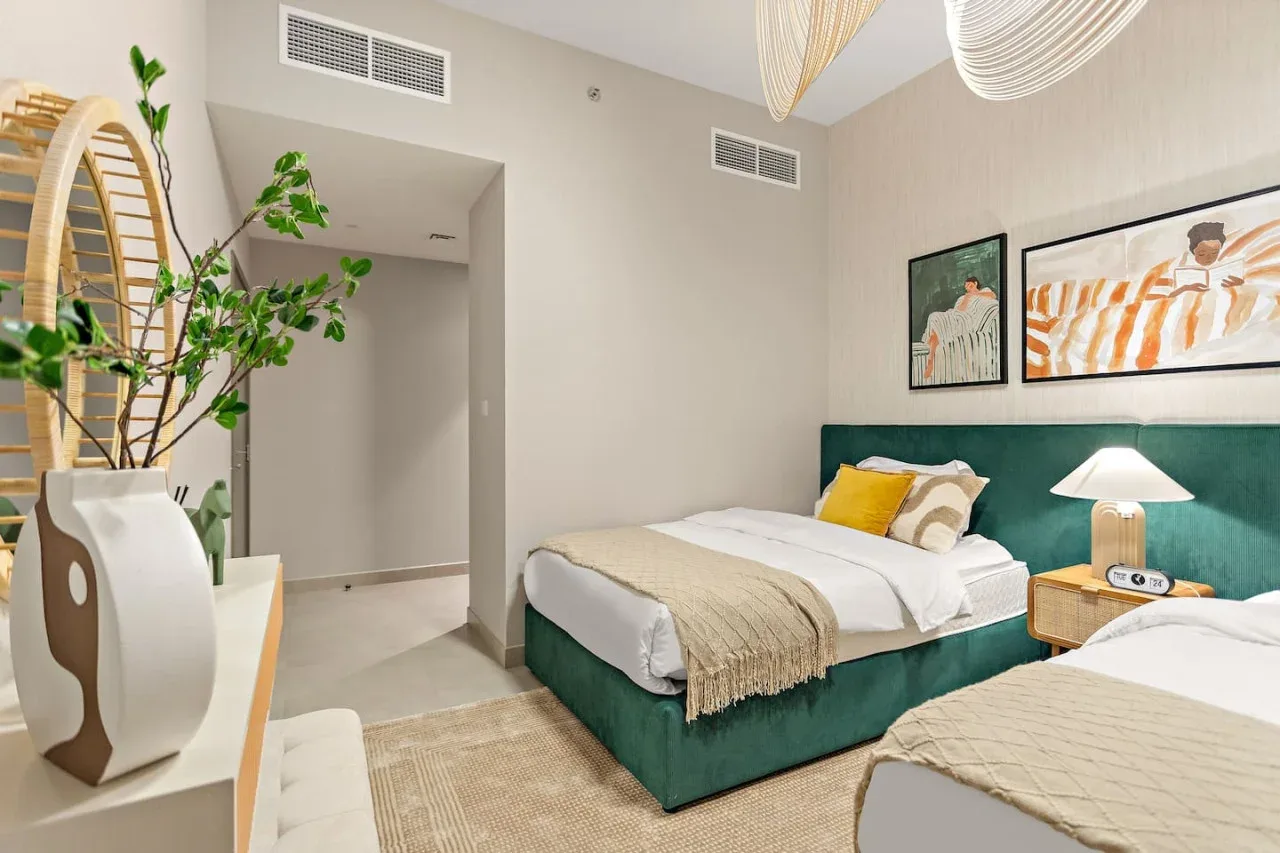 A bright bedroom with a bed, teal headboard, and framed artwork.