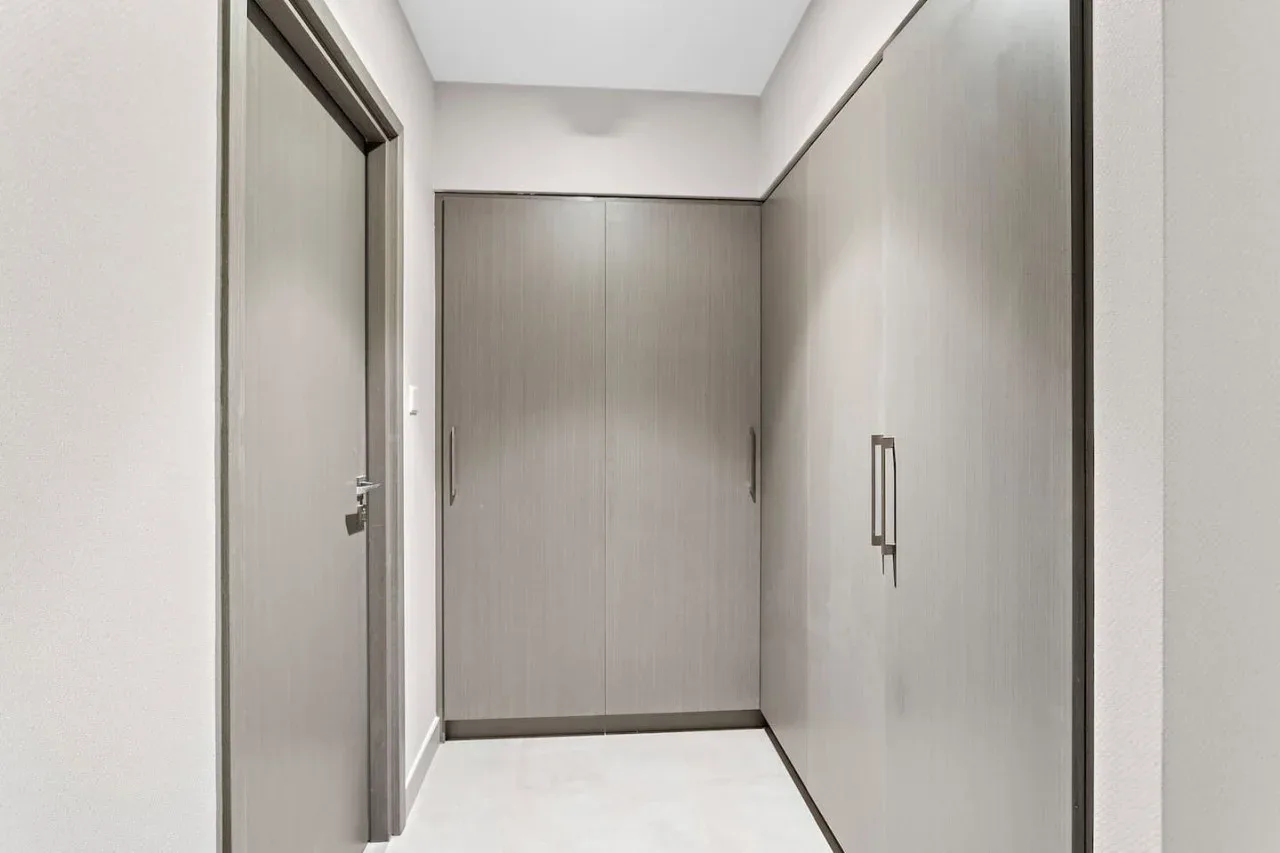 A hallway with gray built-in cabinets and a closed door.