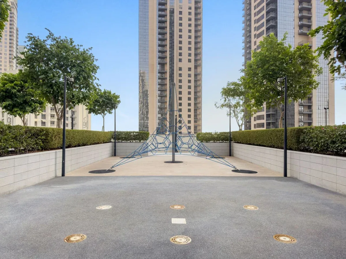 A paved outdoor courtyard with trees and tall residential buildings.