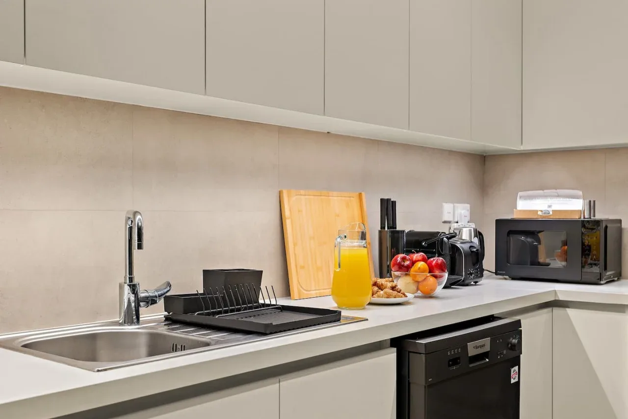 A modern kitchen counter with a sink, appliances, and fruit.