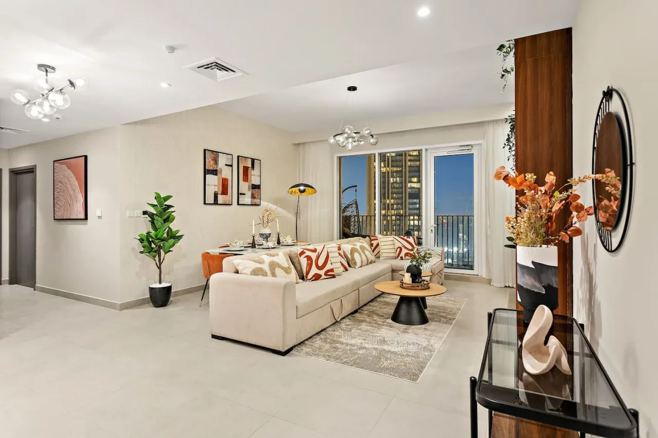 A bright living room with a seating area and glass doors opening onto a balcony.