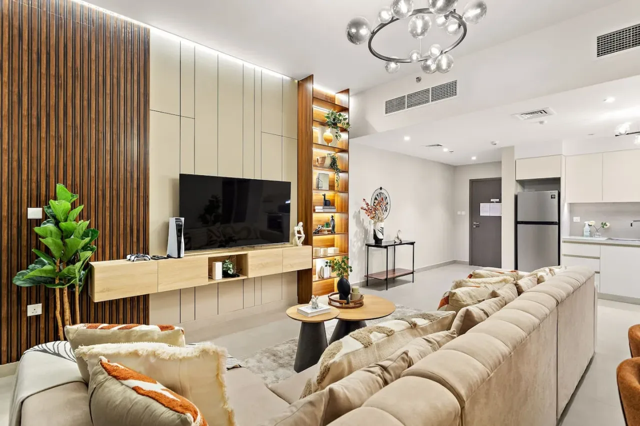 A bright living room with a television wall and open kitchen.