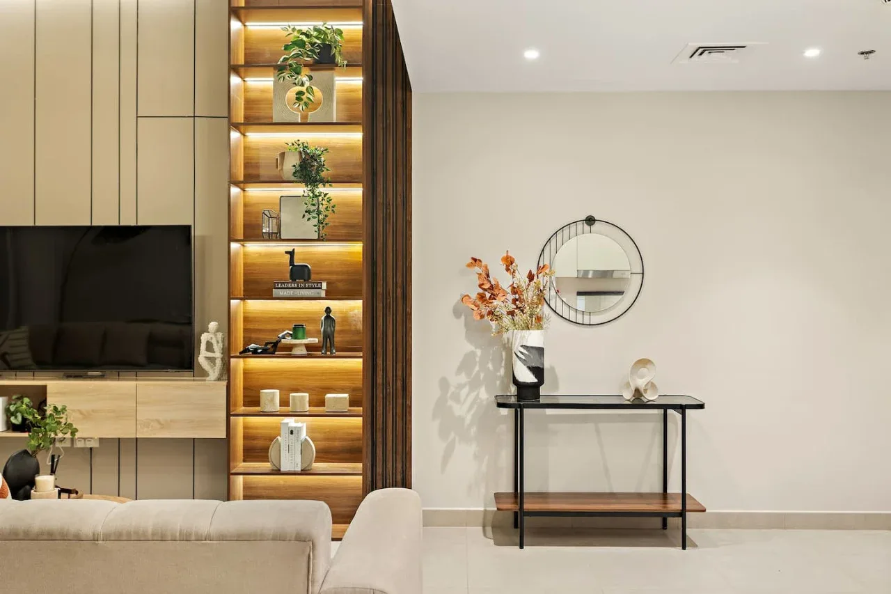 A living room with a television and a console table beneath a round mirror.