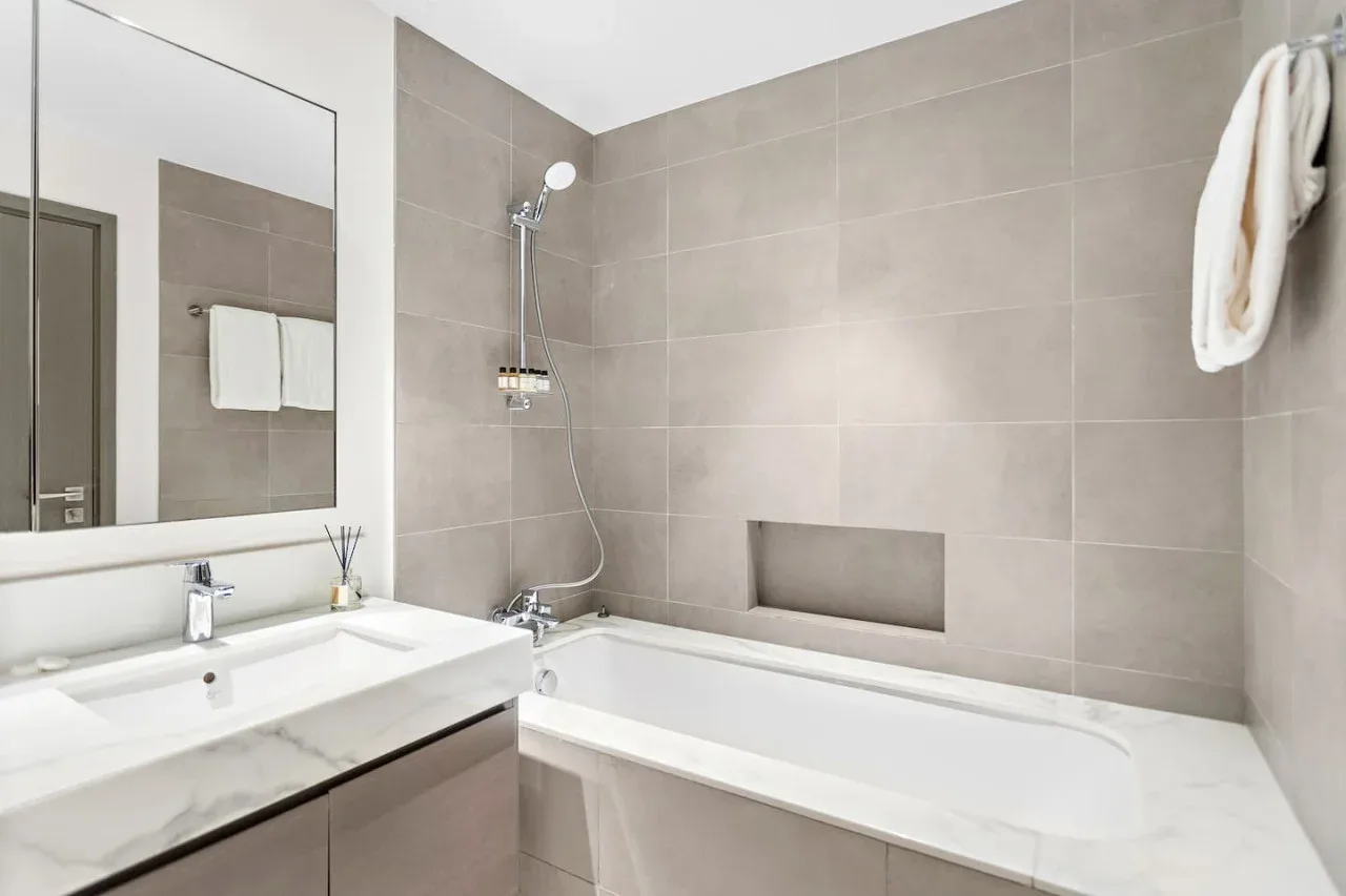 A tiled bathroom with a bathtub, shower, and sink.