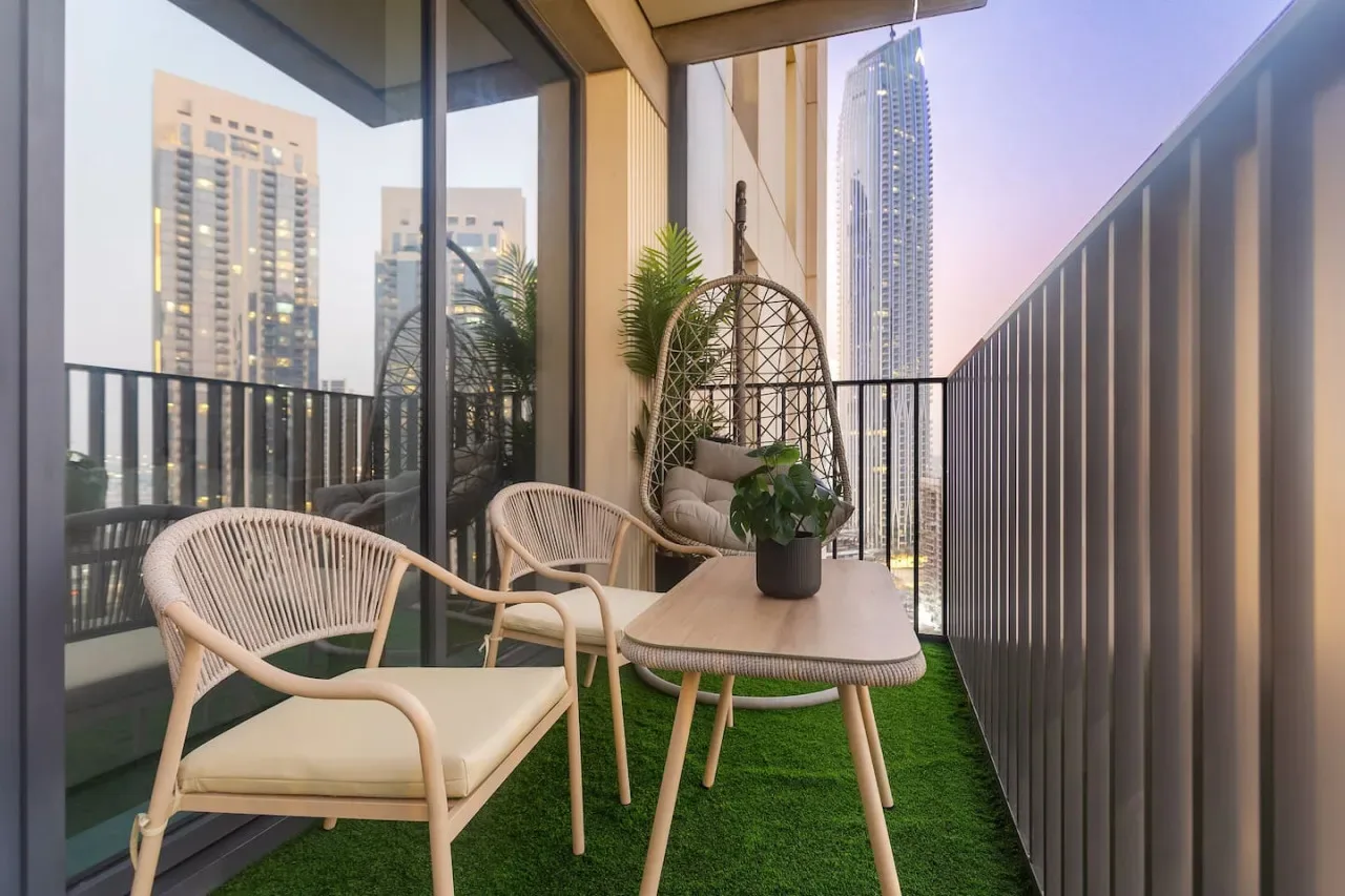 A furnished balcony with seating, a hanging chair, and potted greenery.