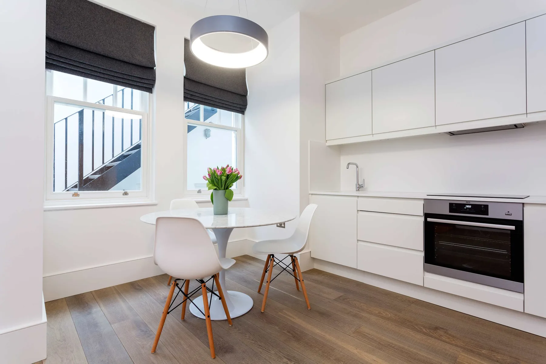 A bright kitchen and dining nook with white cabinets and a small table by the windows.