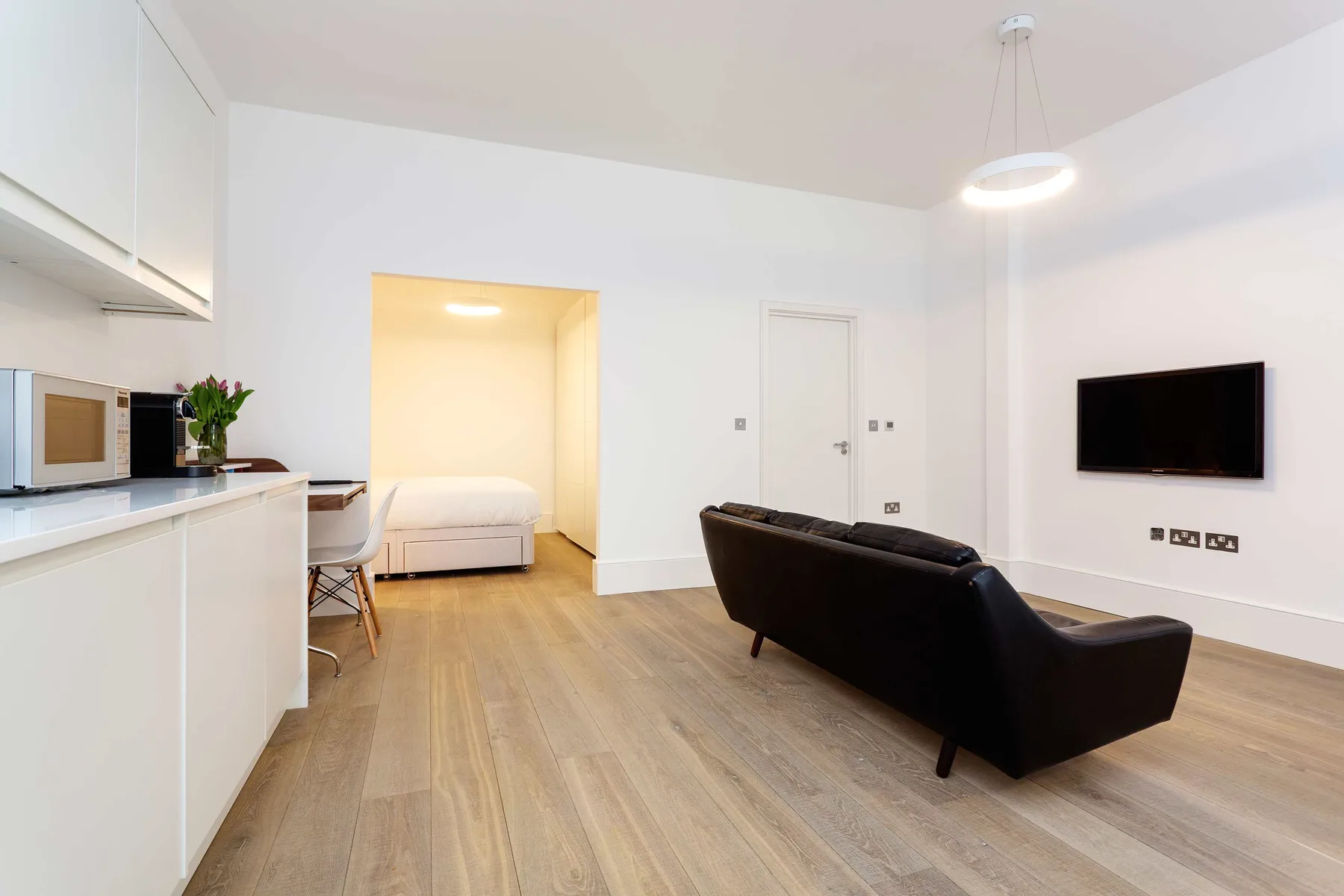 Una luminosa sala de estar abierta con barra de cocina, asientos y televisor.