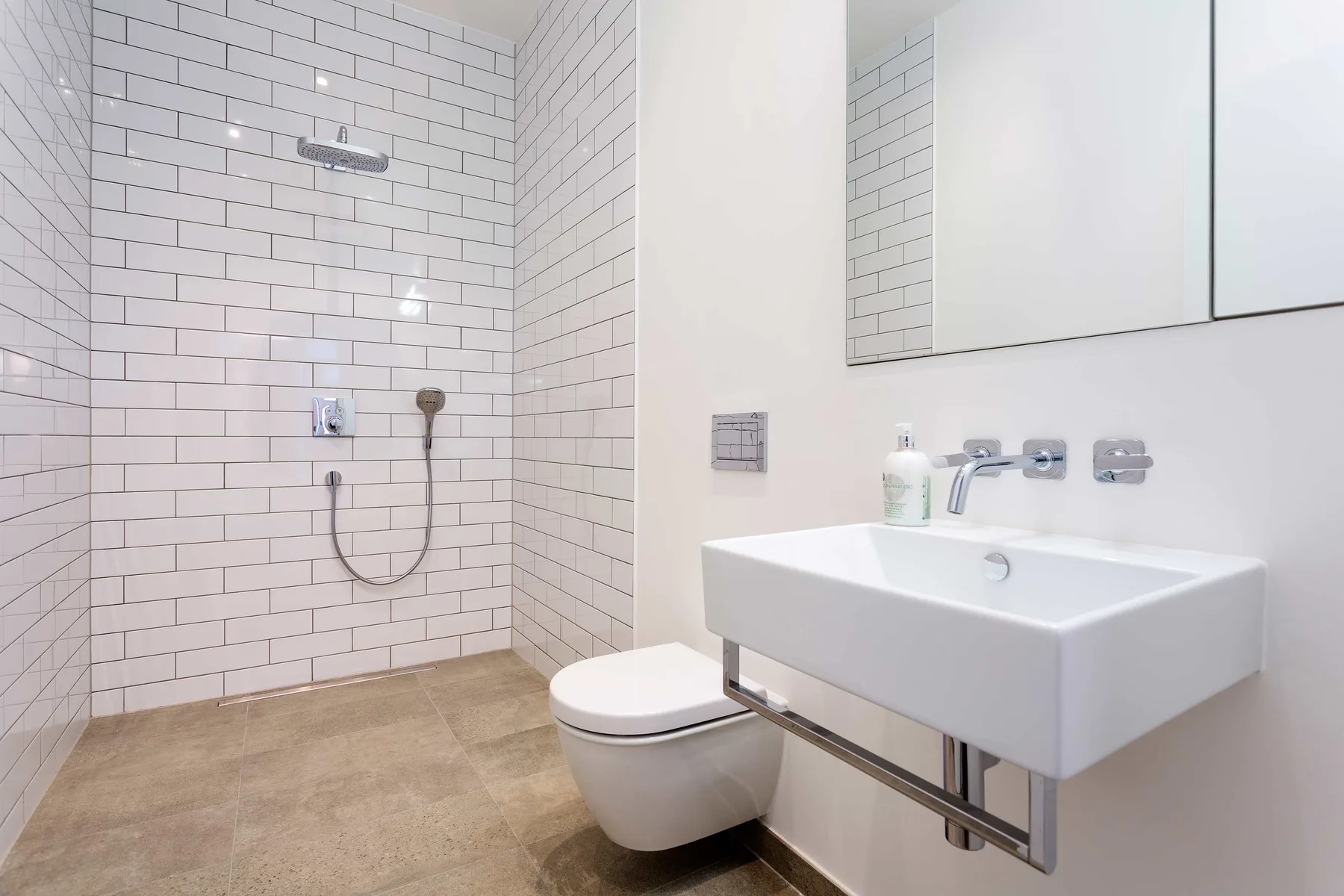 A tiled bathroom with a shower, toilet, and wall-mounted sink.