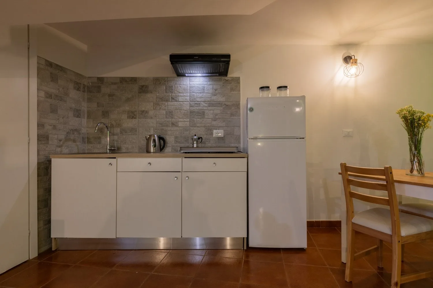 A compact kitchen with a countertop, refrigerator, and dining table.