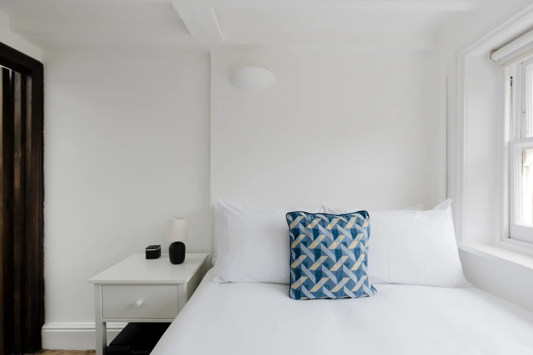 Un dormitorio luminoso con una cama y una mesita de noche.
