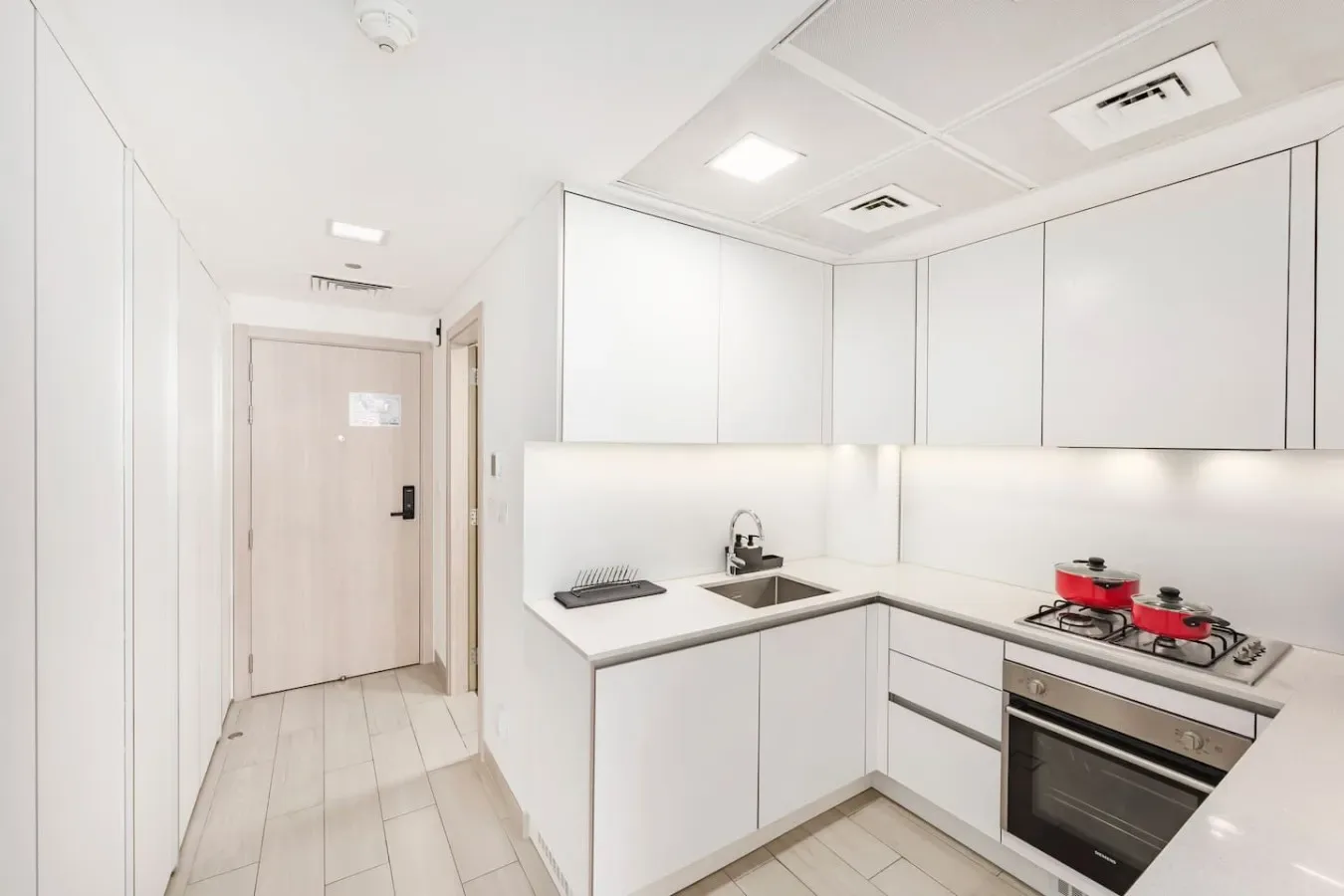 A bright white kitchen with an L-shaped counter and built-in oven.