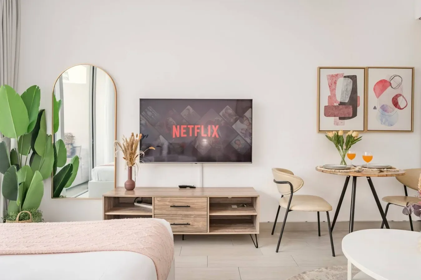 A bright bedroom with a bed, a television, and a small dining table.