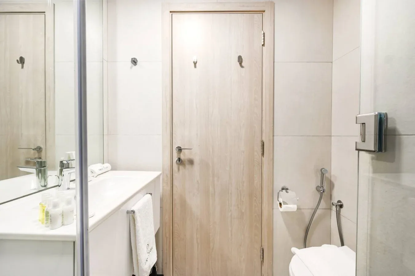 A bright bathroom with a sink, mirror, and toilet.