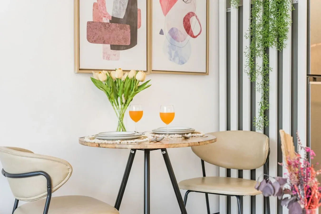 Dining area with a round table, two place settings, and framed artwork.