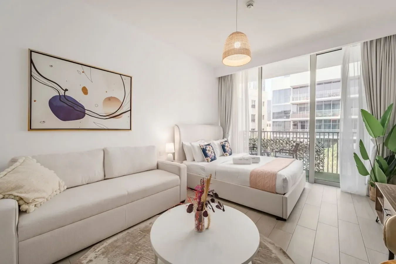 A bright bedroom with a bed, seating area, and large windows.