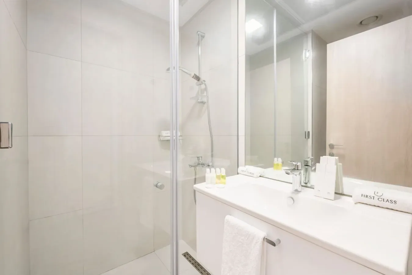 A bright bathroom with a glass shower and a wide sink counter.