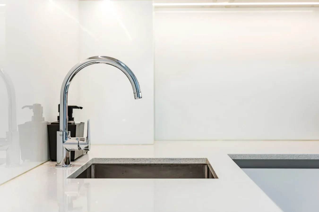 A bright kitchen counter features a chrome faucet and inset sink.