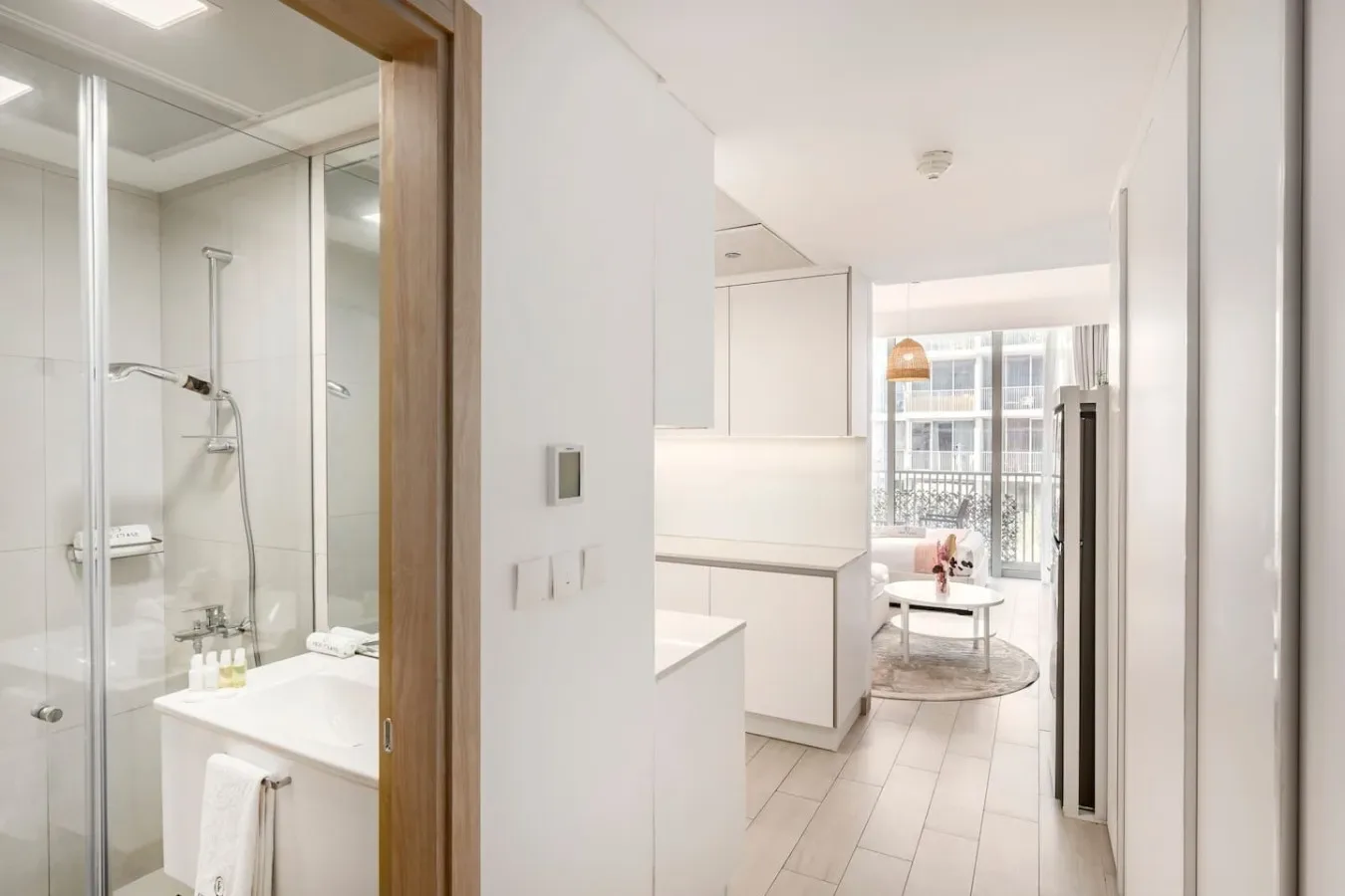 A bright bathroom opens onto a kitchen and dining area with a balcony view.
