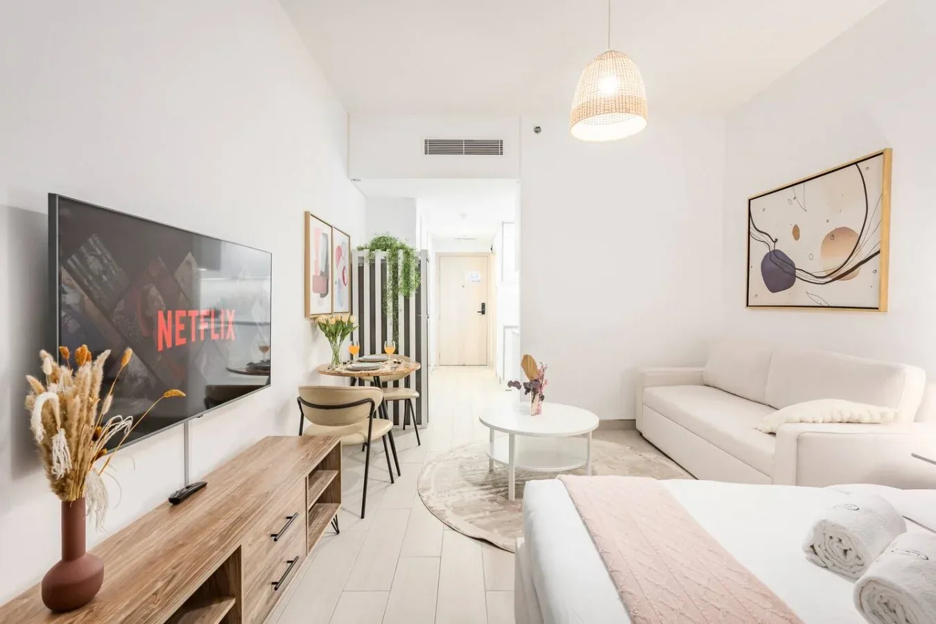 A bright living area with seating, a television, and a small round table.