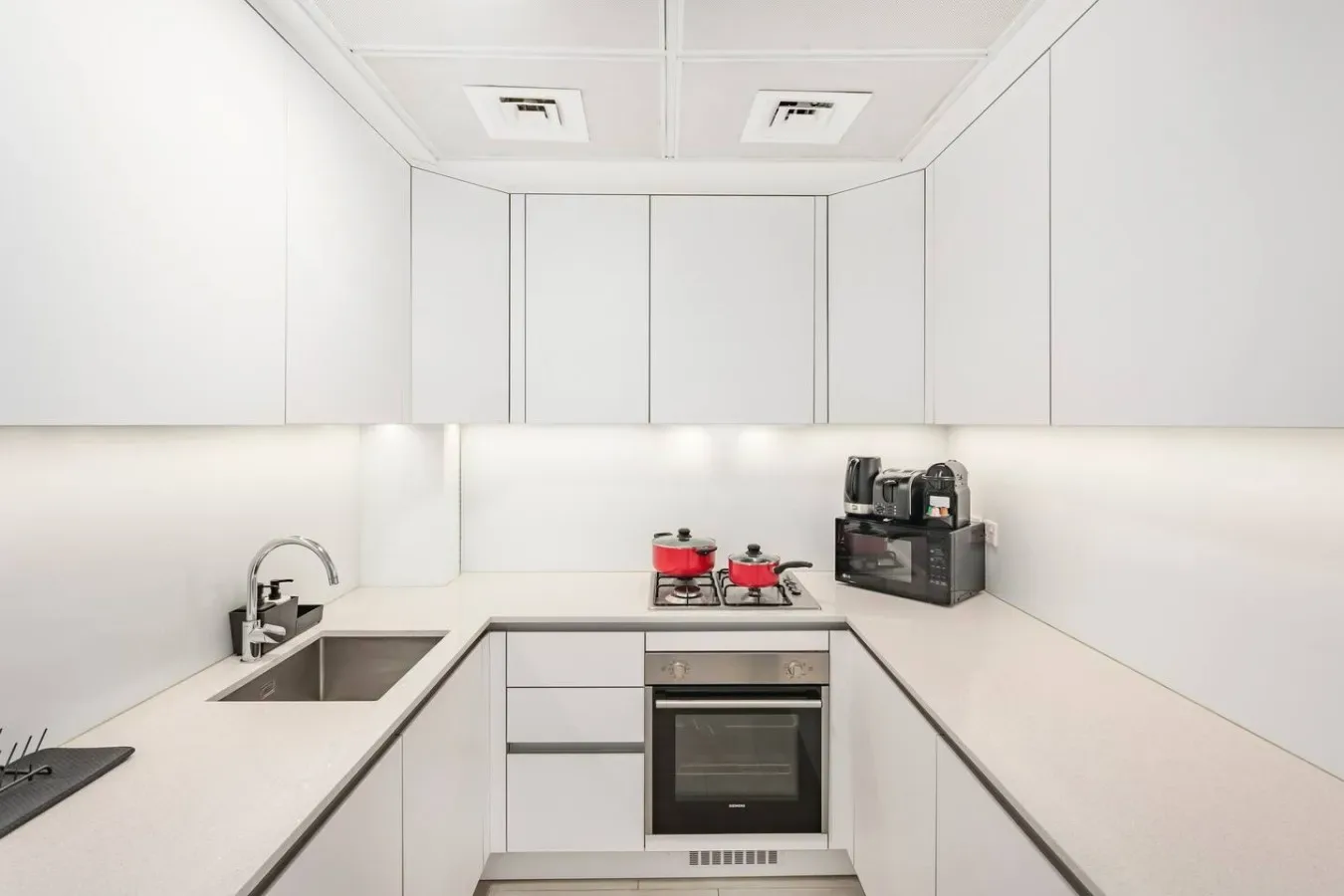 A bright modern kitchen with a sink, cooktop, and built-in oven.