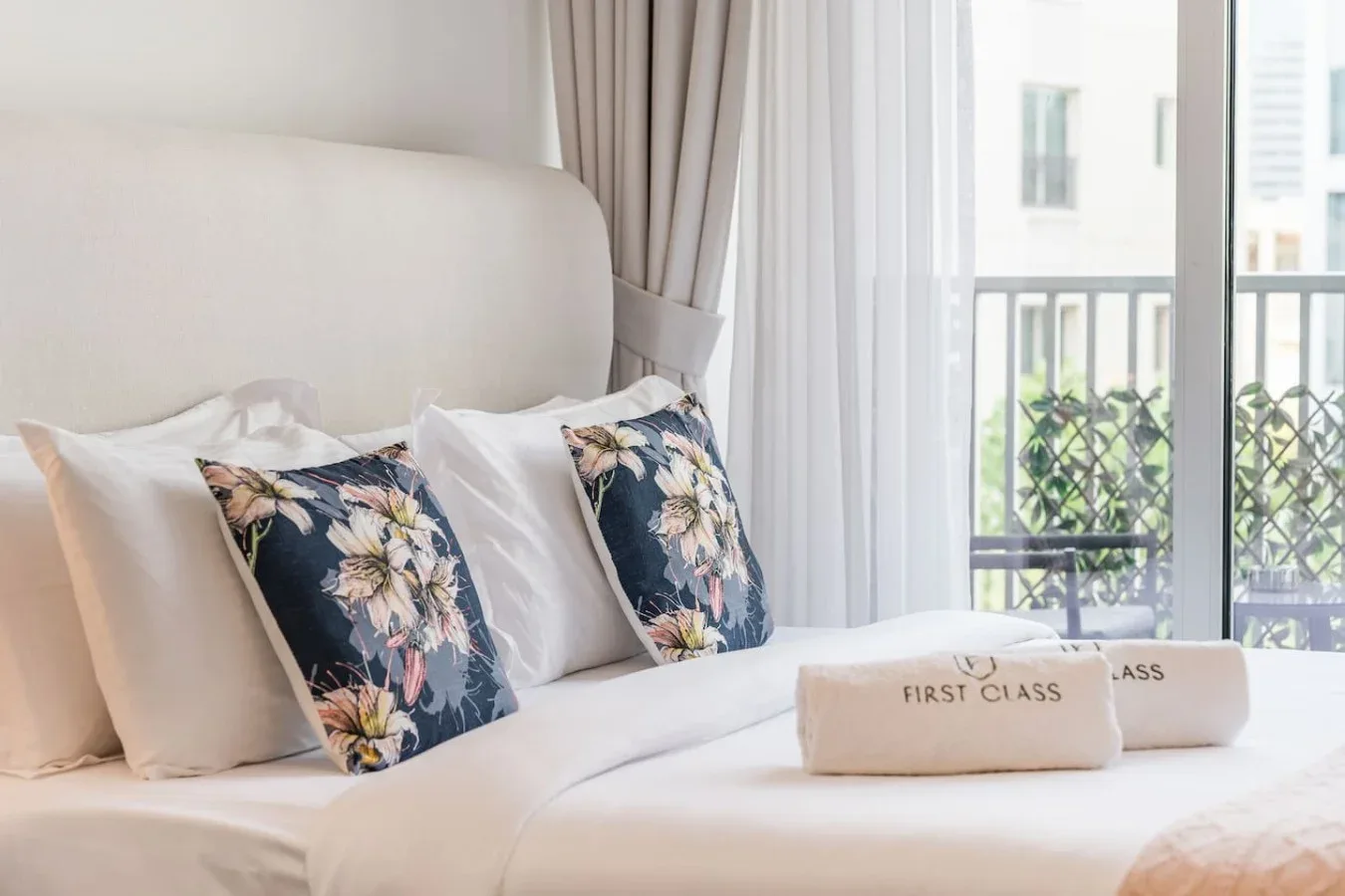 A bedroom with floral accent pillows on a bed beside a bright window.