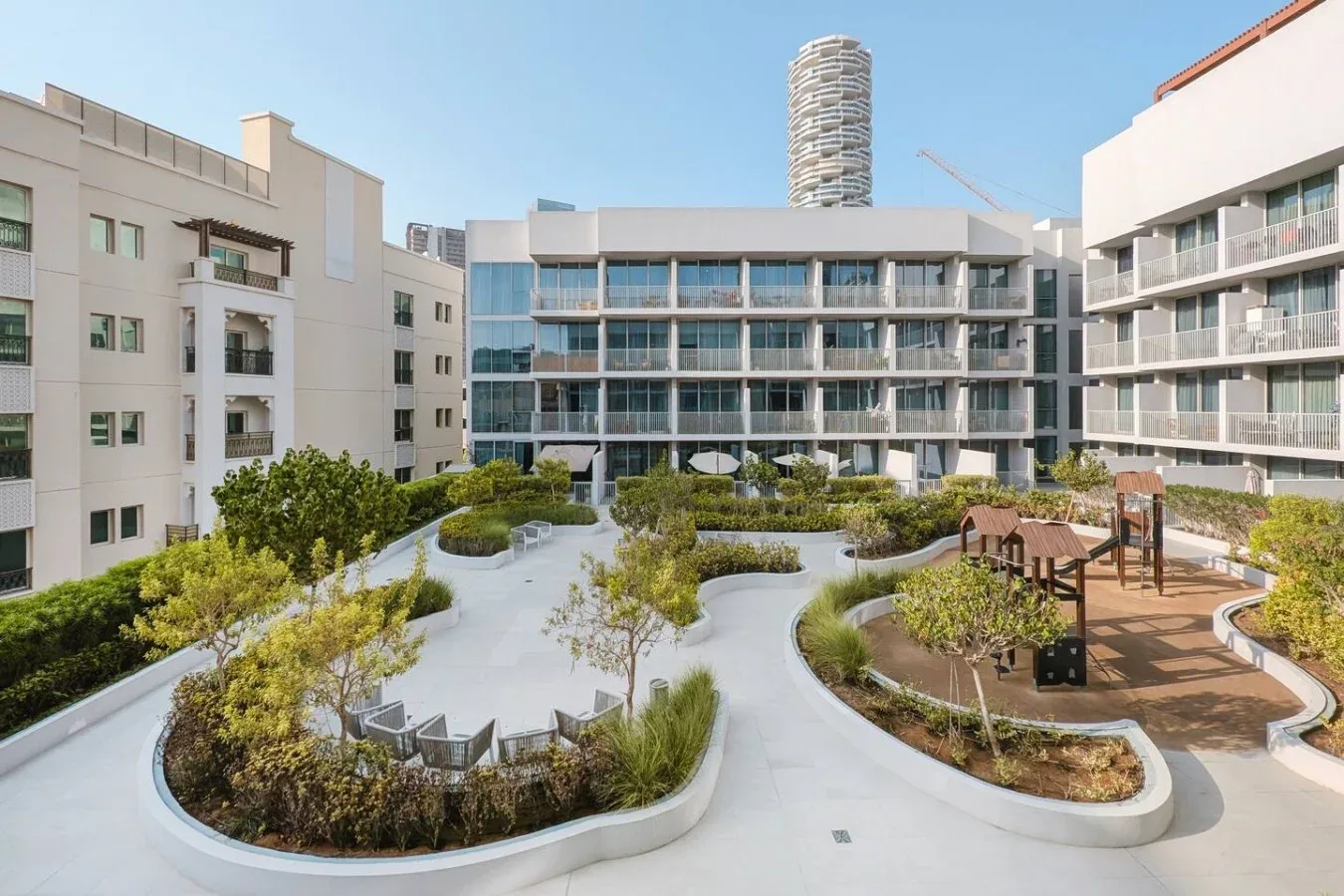 A landscaped courtyard with winding paths and seating between modern buildings.