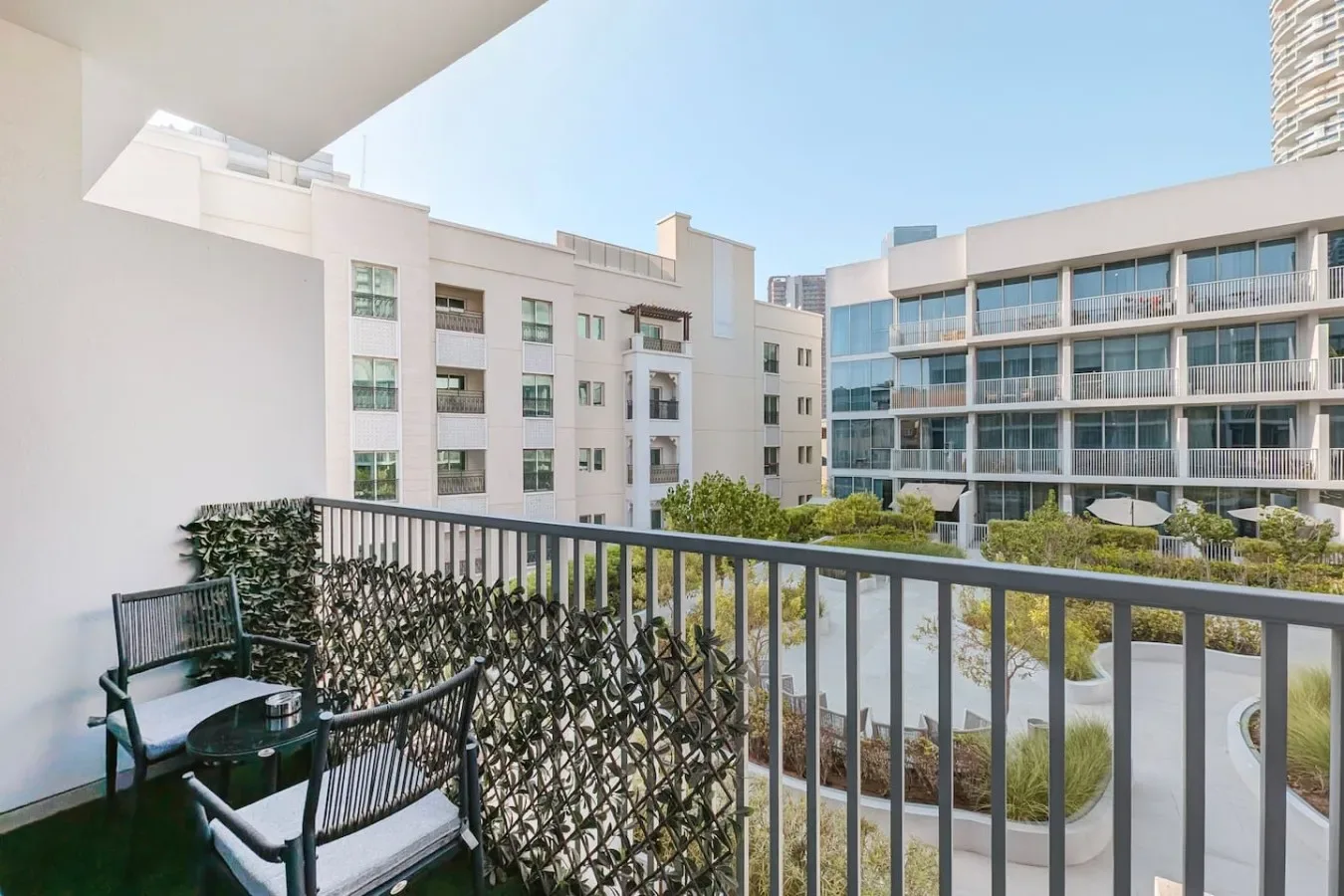 A balcony overlooks a landscaped courtyard and modern multi-story buildings.