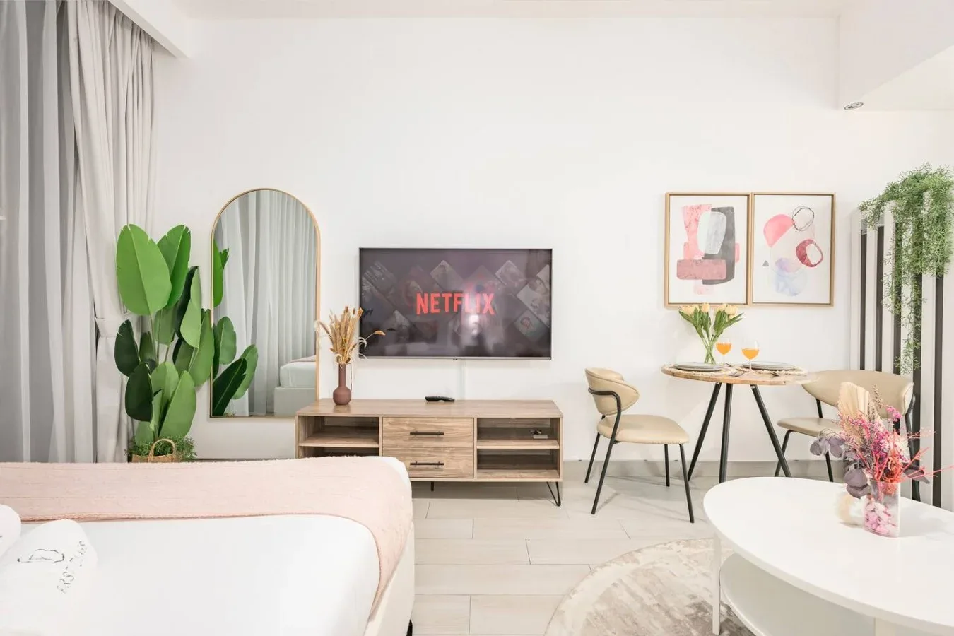 A bright studio room with a bed, seating area, and dining table.