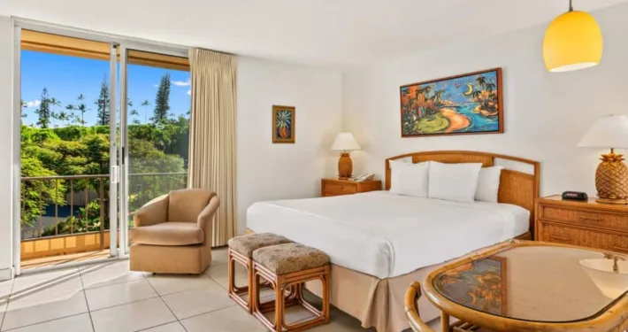 Habitación de hotel con cama, asientos de comedor y puertas corredizas que dan a la terraza exterior