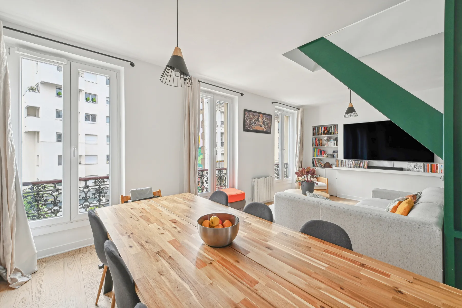 A bright open-plan living and dining room with a wooden dining table and seating.