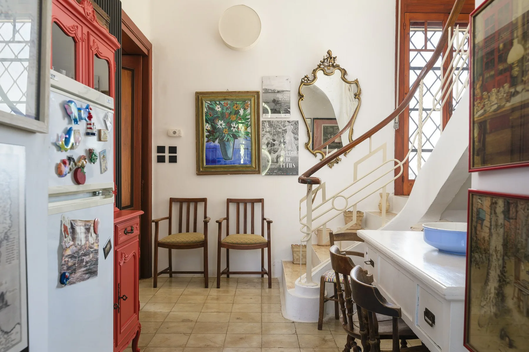 A bright kitchen with a staircase and two chairs beside the wall.