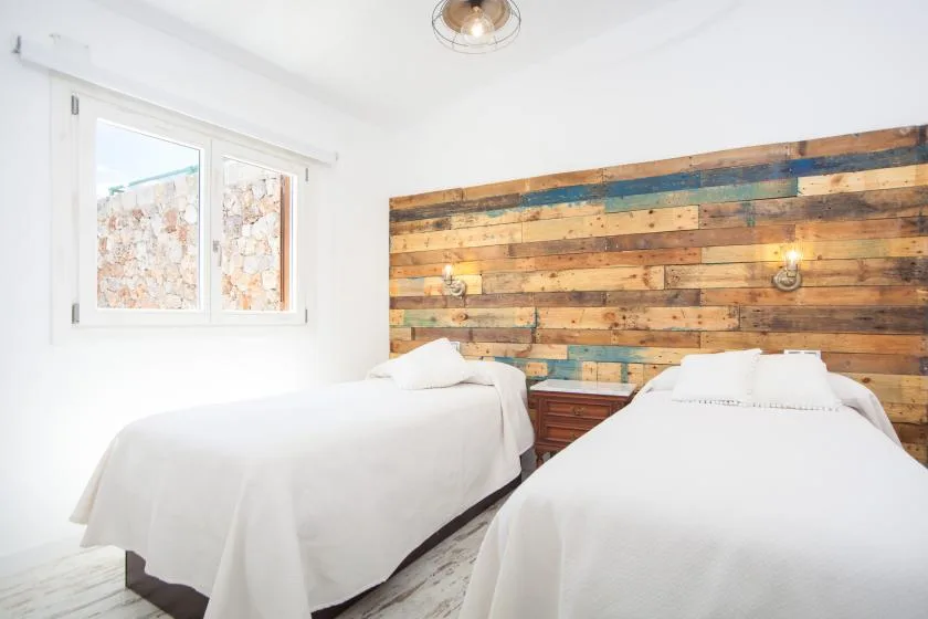 A bright bedroom with two beds beside a colorful wood accent wall.