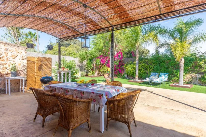 A shaded outdoor dining area opens onto a garden with palm trees.