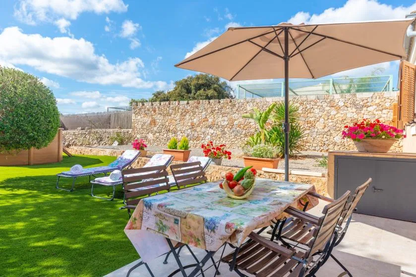 Outdoor dining area with a table and seating beneath a large umbrella.