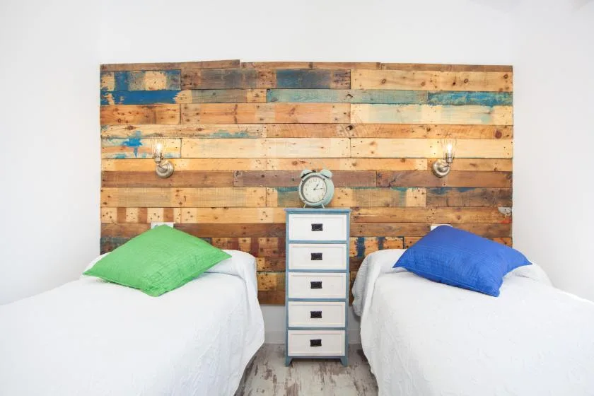 A bedroom with two beds beside a small central chest of drawers.