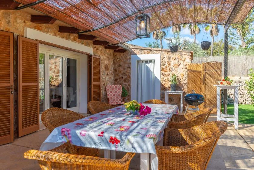 An outdoor dining patio with a covered table and wicker seating.