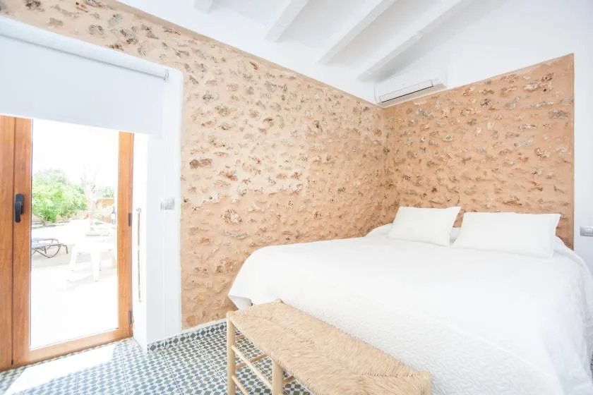 A bright bedroom with a white bed beside a wooden-framed glass door.