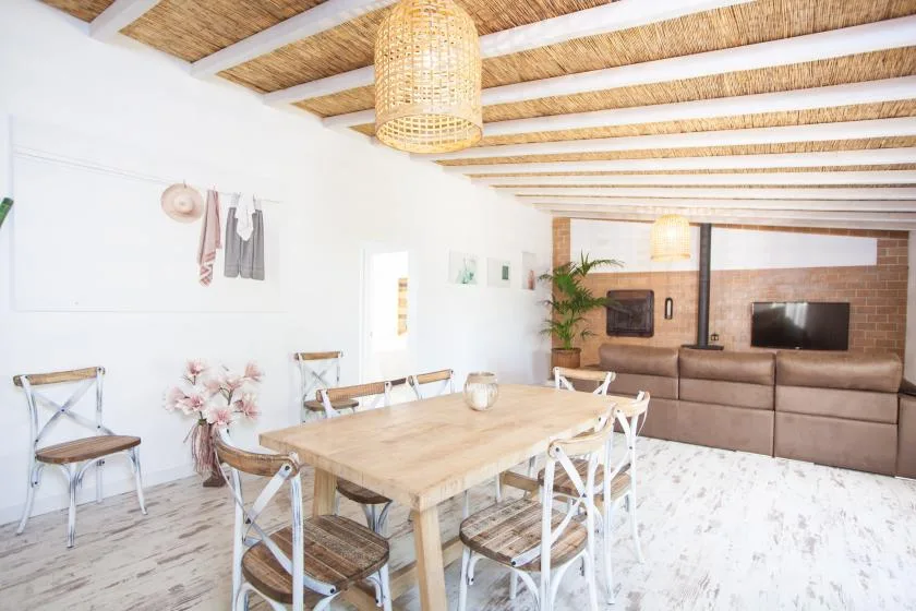 A dining area with a wooden table and chairs beside a living room seating area.