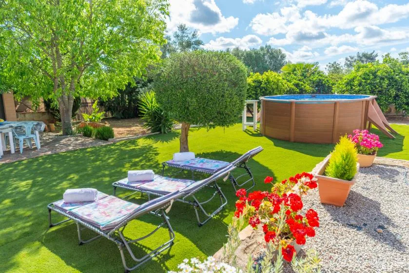 A sunny garden with lawn seating, colorful flowers, and an above-ground pool.