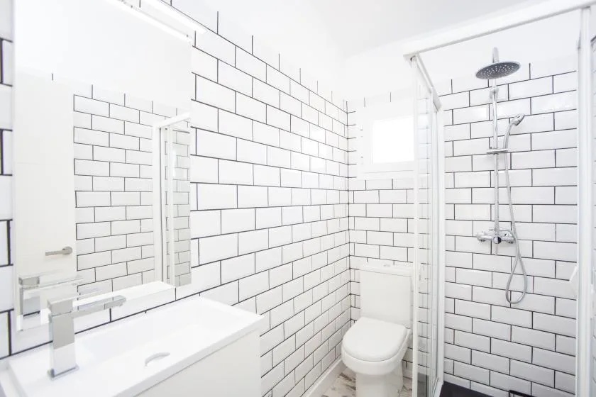 A bright tiled bathroom with a sink, toilet, and shower.