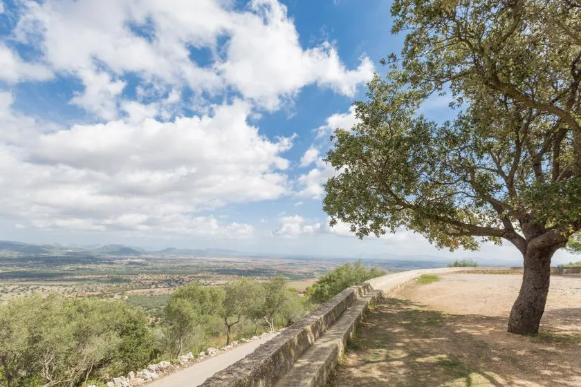 A scenic outdoor viewpoint overlooks a broad valley beneath a partly cloudy sky.