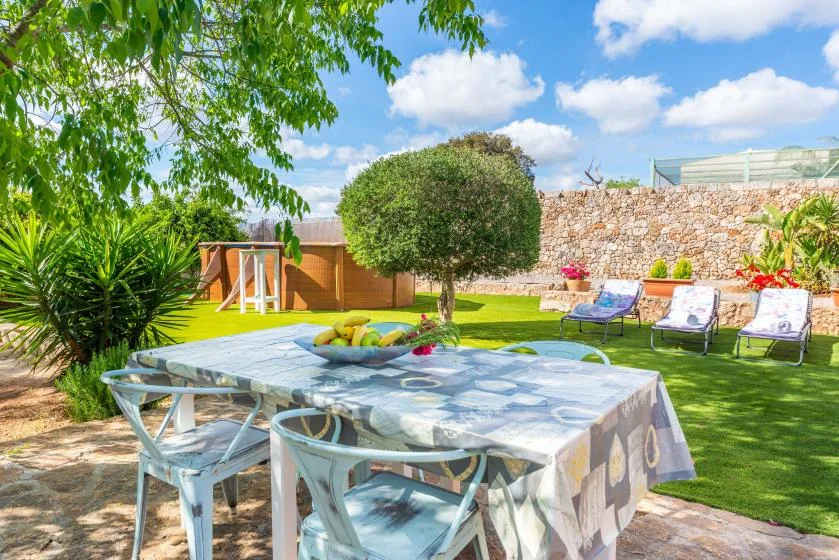 A garden dining area with a table, chairs, lawn, and outdoor loungers.