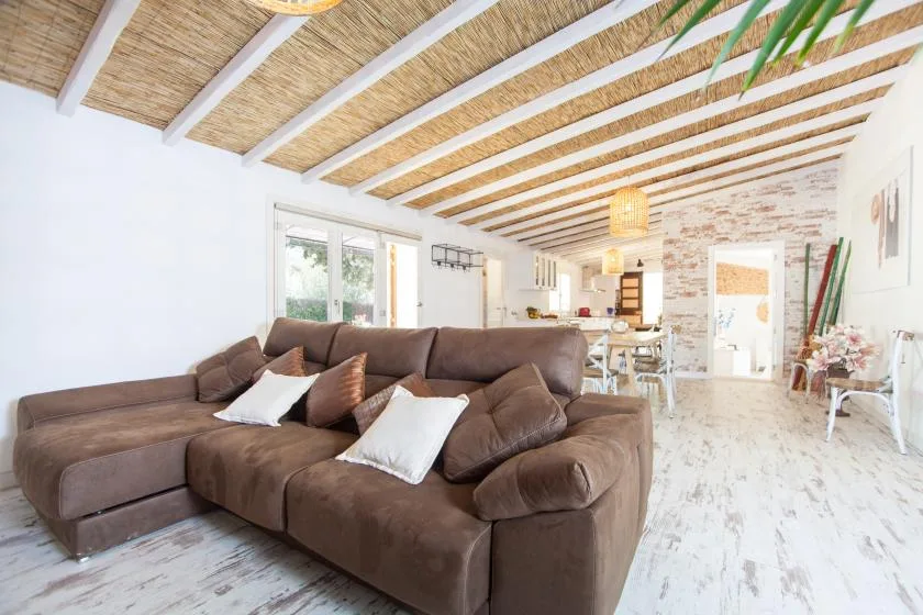 A bright open-plan living room with brown seating and a dining area beyond.