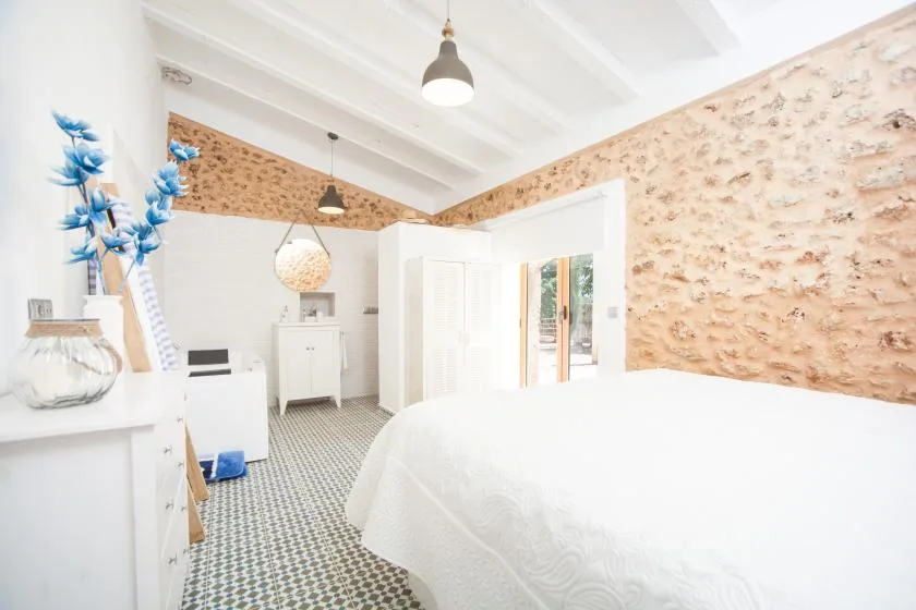 A bright bedroom with a white bed and patterned tile floor.